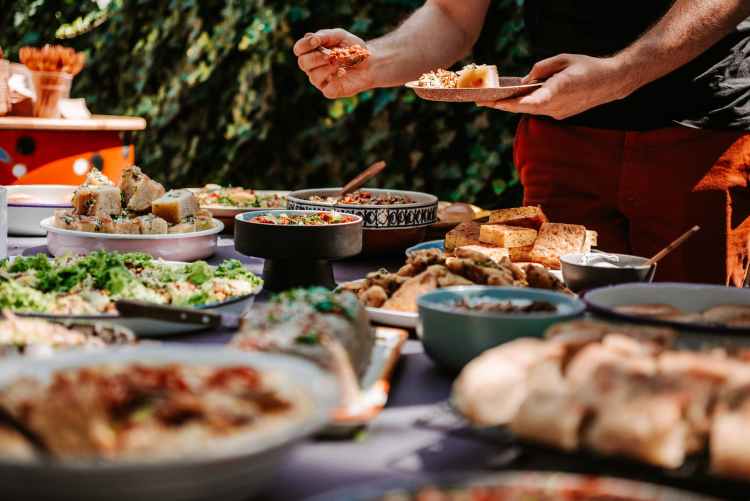 man filling his plate with food from buffet table