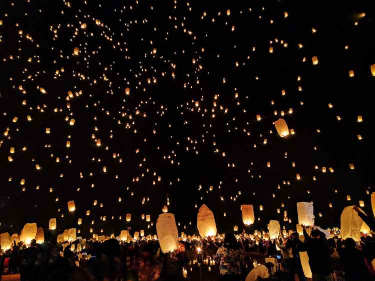 group of people throwing paper lantern on sky during night