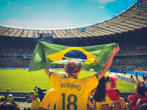 Crispin Hull / Boycotting FIFA World Cup 2022 man raising brazil flag inside football stadium