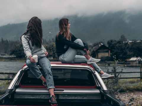 The Weekend Guide. two women sitting on vehicle roofs