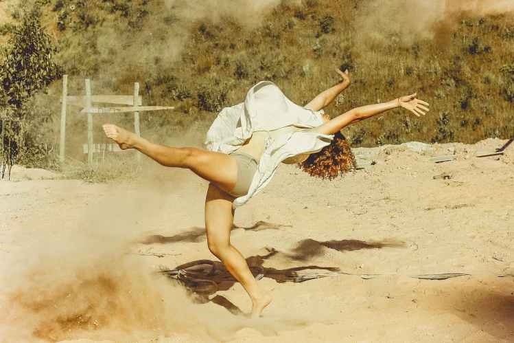 woman wearing white dress dancing on brown sand